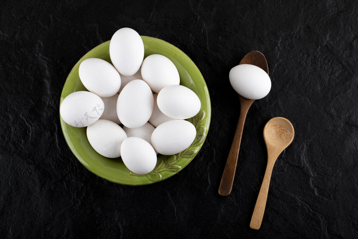 有机一堆生鸡蛋放在绿色的盘子里 用木勺食物天然生的