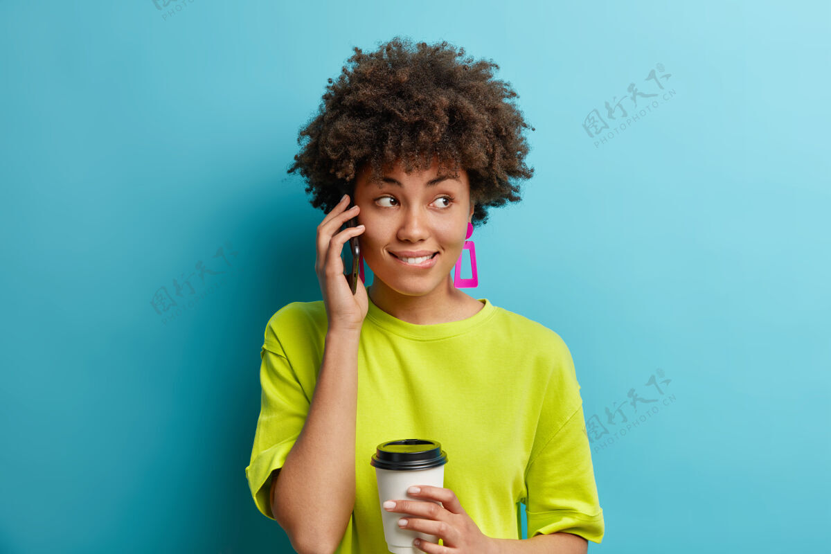 思想可爱体贴的黑皮肤女人有电话交谈集中在一边沉思地咬嘴唇喝外卖咖啡欢呼蓝色电话
