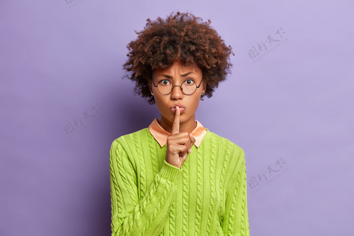 神秘神秘严肃的美国黑人年轻女子做了一个沉默的手势标志紫色手指