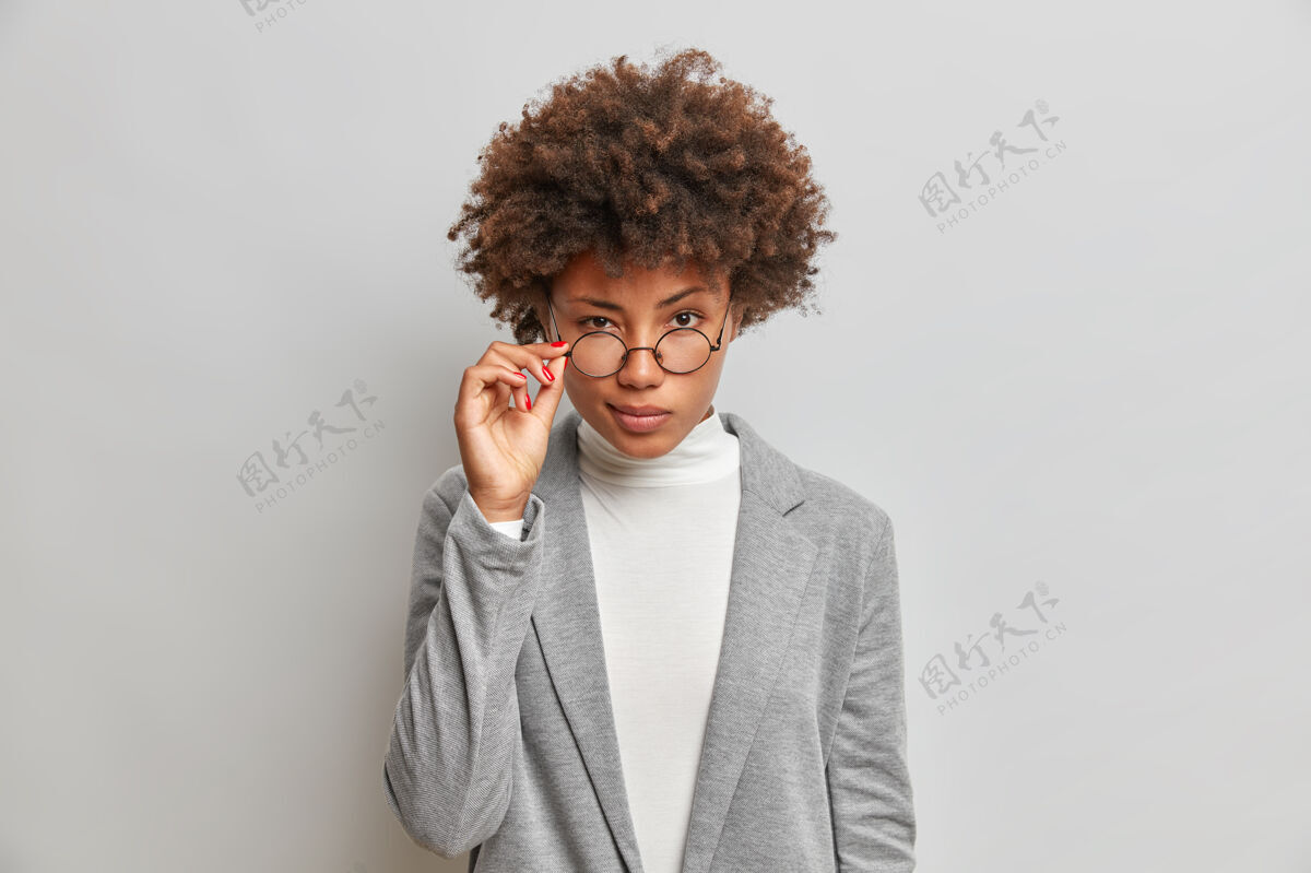 白色美丽的非洲裔美国女人透过圆眼镜聚精会神地看成功深色凝视