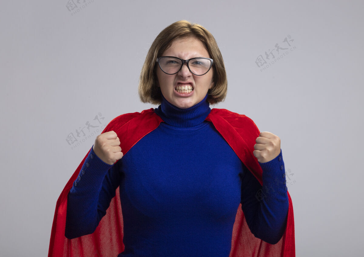 市民愤怒的年轻金发女超级英雄戴着红斗篷看着前面紧握的拳头孤立在白墙上眼镜人衣服
