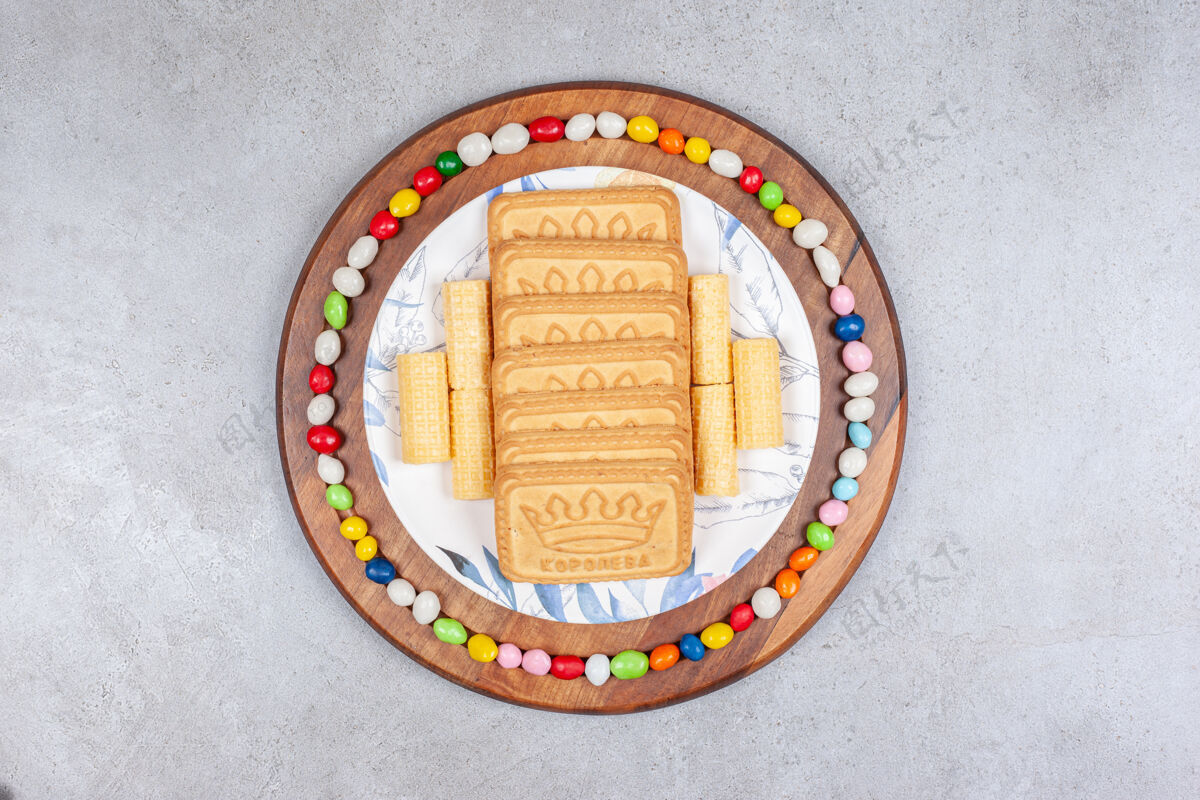 糖果饼干排成一排放在盘子里 周围放着糖果 放在大理石背景的木板上高质量的照片营养味道糖果