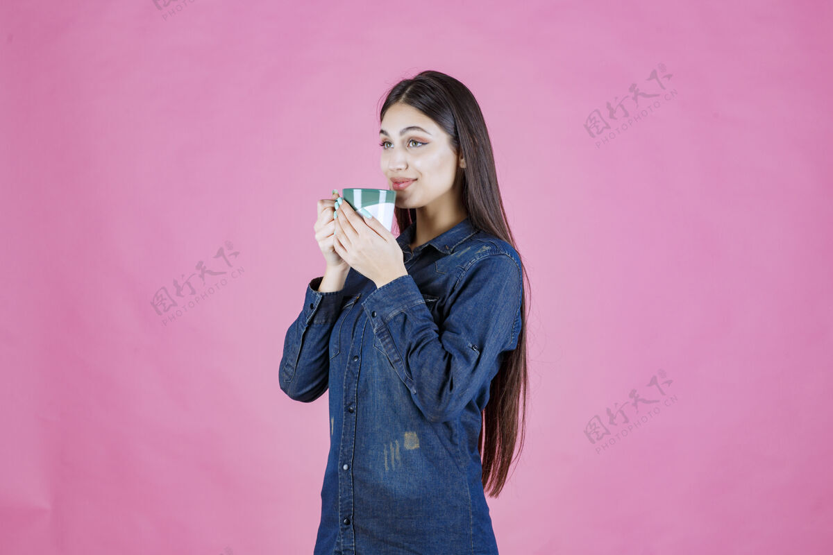 人类女孩拿着一个白绿色的咖啡杯 闻着品味姿势美食