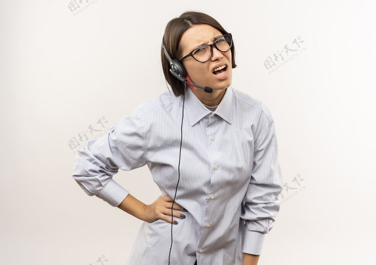 手未出租的年轻呼叫中心女孩戴着眼镜和耳机把手放在腰部隔离在白色背景与复印空间电话年轻穿