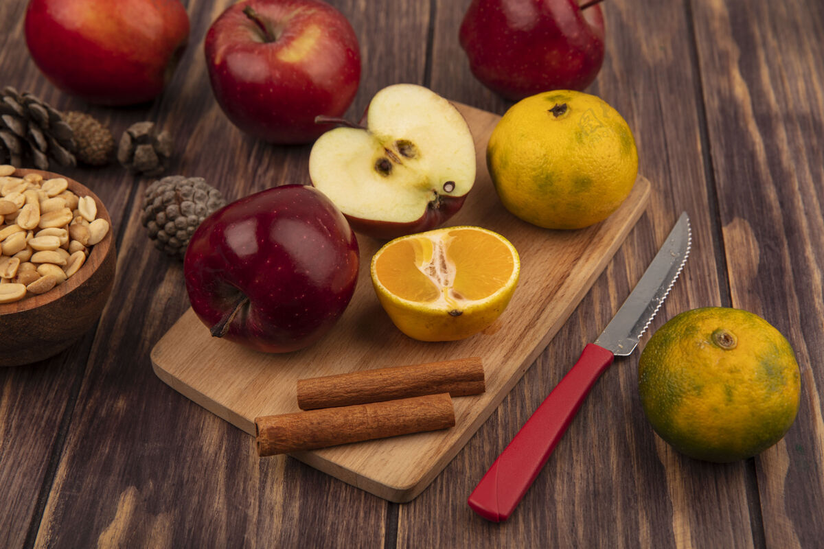 木板有机苹果的俯视图在木制的厨房板上 有半个橘子和肉桂枝 刀上有花生 在木制的碗上 苹果被隔离在木制的背景上苹果一半视图