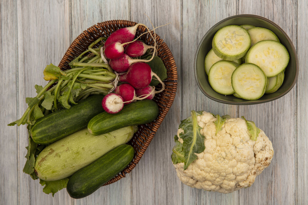 黄瓜健康蔬菜的顶视图 如黄瓜 西葫芦和萝卜 放在桶上 花椰菜被隔离在灰色的木制背景上蔬菜观点健康