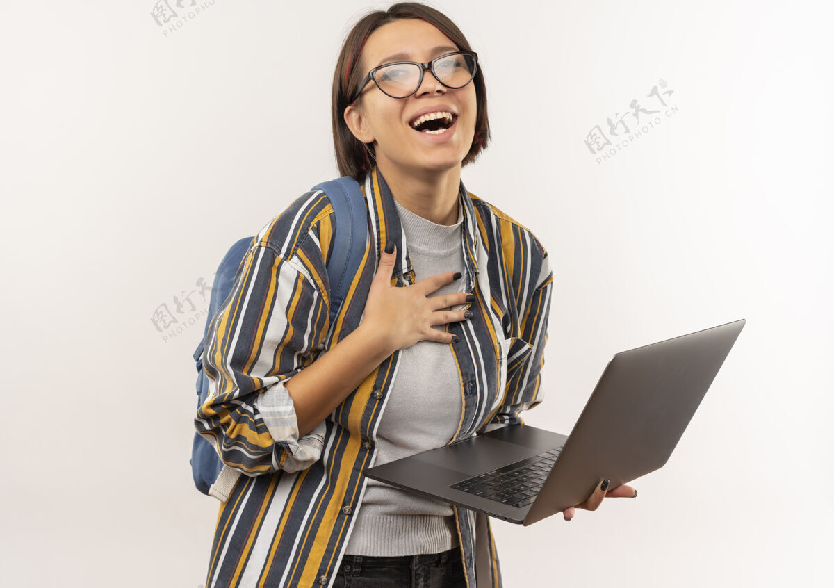 笔记本电脑快乐的年轻女学生戴着眼镜 背着包拿着手提电脑 手放在胸前 隔着白色衣服年轻眼镜举行