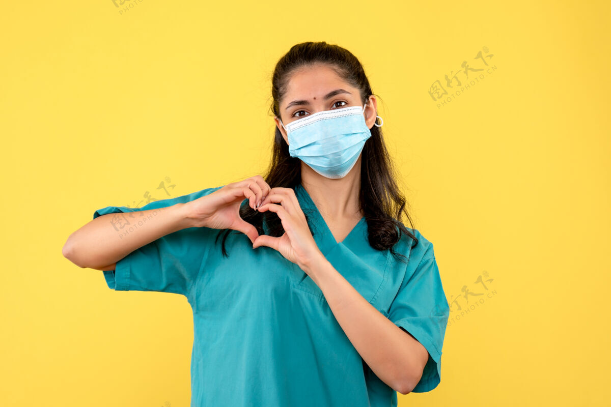 漂亮前视图带医用面罩的女医生用手指做心脏标志肖像符号手指