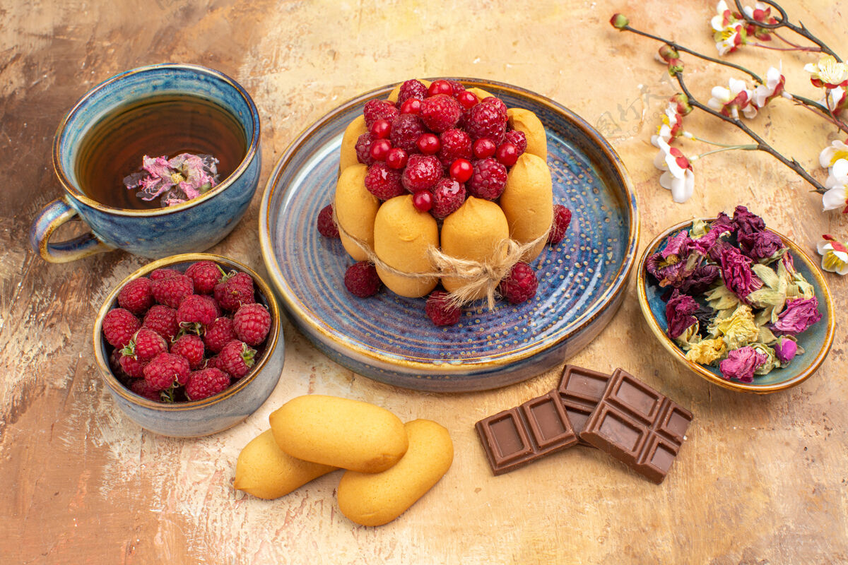 早餐热凉茶软蛋糕和水果巧克力条在混合颜色的桌子上的侧视图草药软蛋糕草莓