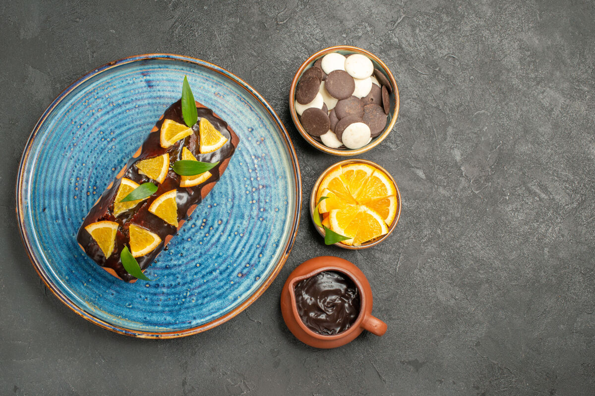 黑巧克力黑桌子上装饰着柠檬和巧克力的软蛋糕的侧视图金属软蛋糕壁板