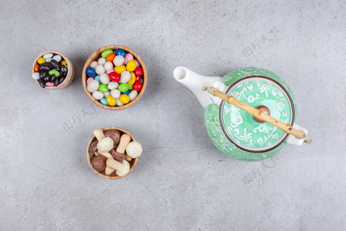 营养在大理石背景上华丽的茶壶旁边放着几碗糖果和蘑菇巧克力高质量的照片茶巧克力风味