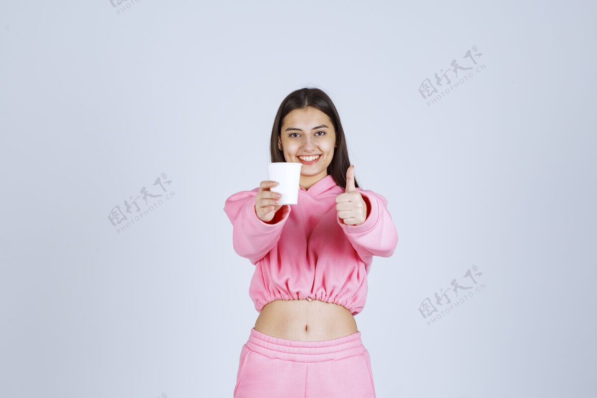 喜欢穿着粉色睡衣的女孩捧着咖啡杯 享受着咖啡的味道休闲女性姿势