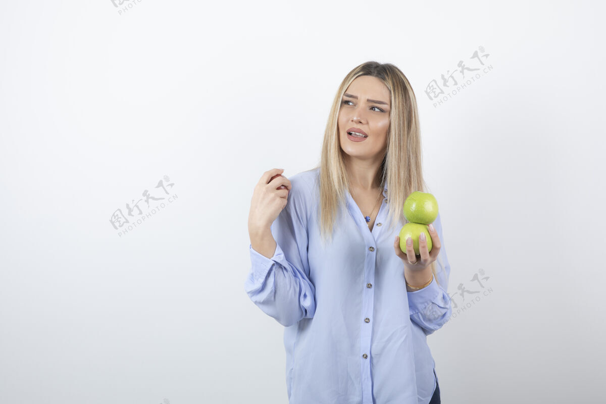 人一个美丽迷人的女模特站着拿着新鲜苹果的肖像照食物人模特
