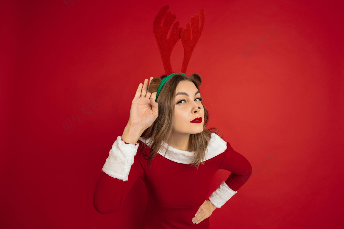在线美丽的女人像圣诞鹿隔离在红墙的概念拥抱鹿人