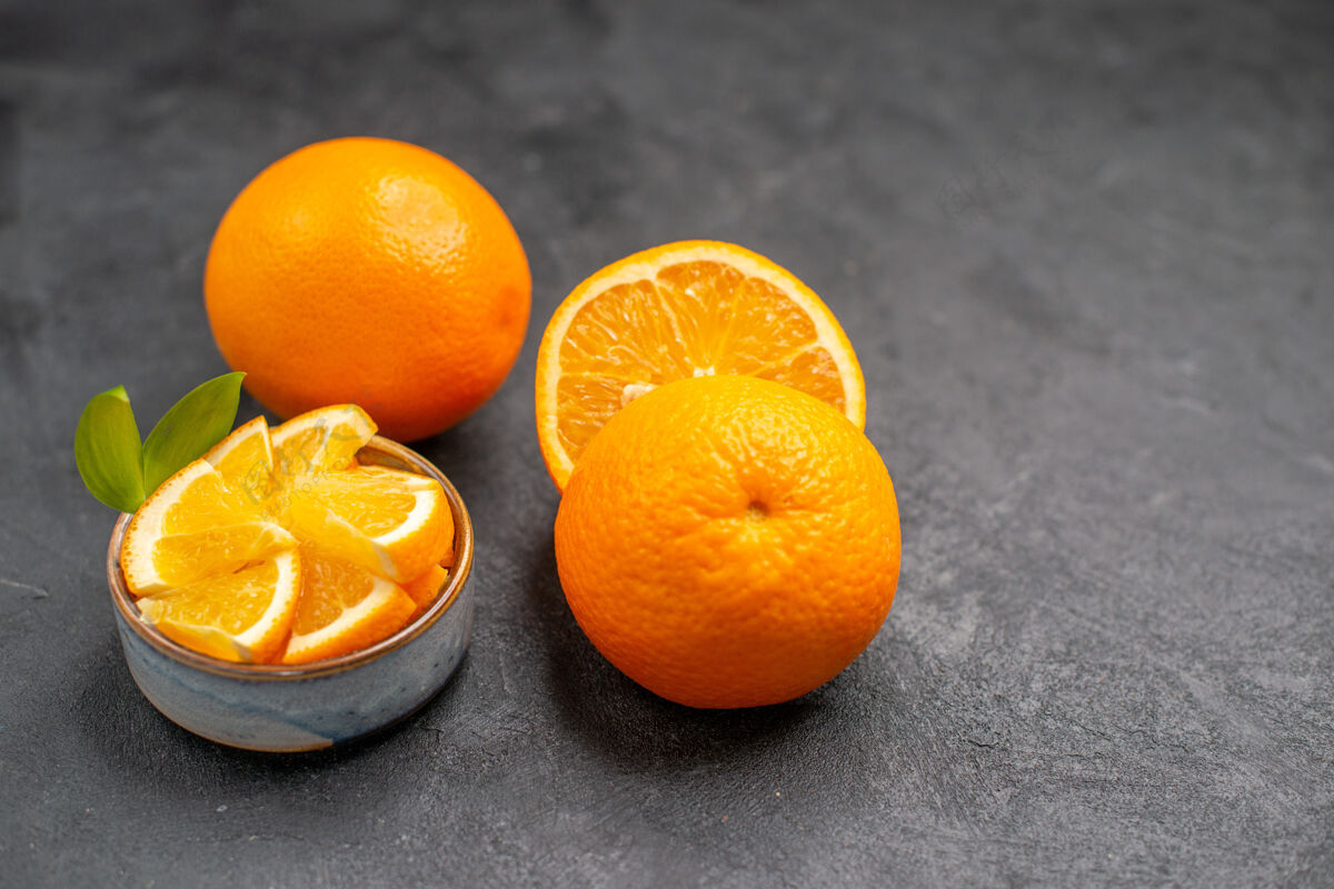 可食用水果黑暗的桌子上的整个和切碎的新鲜橙子的特写镜头完整柑橘成熟