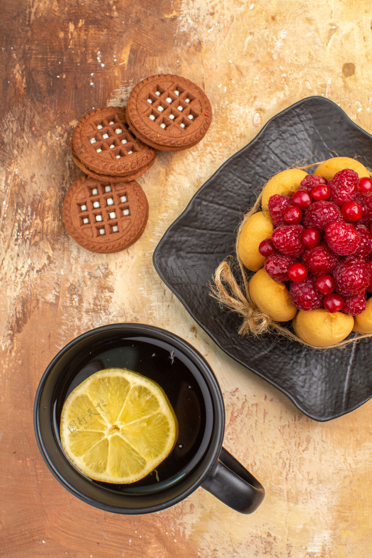 草莓在棕色盘子里放一块蛋糕和饼干 在五颜六色的桌子上放一杯茶茶饼干健康
