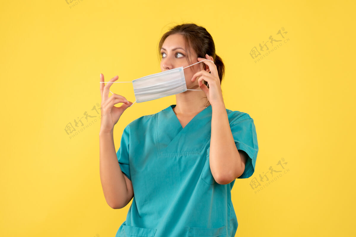 面具前视图穿着医用衬衫的女医生在黄色背景上摘下了她的面具服用肖像病毒