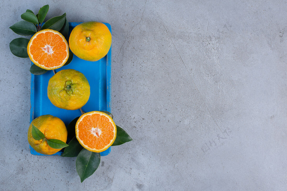 健康橘子和叶子放在一个蓝色的小盘子里 背景是大理石饮食柑橘天然