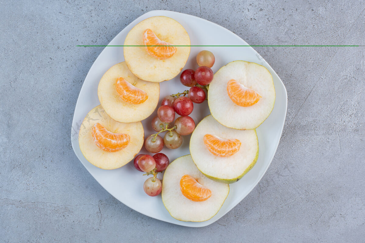橘子把苹果 梨 橘子和葡萄片放在大理石背景上的盘子里拼盘水果美味