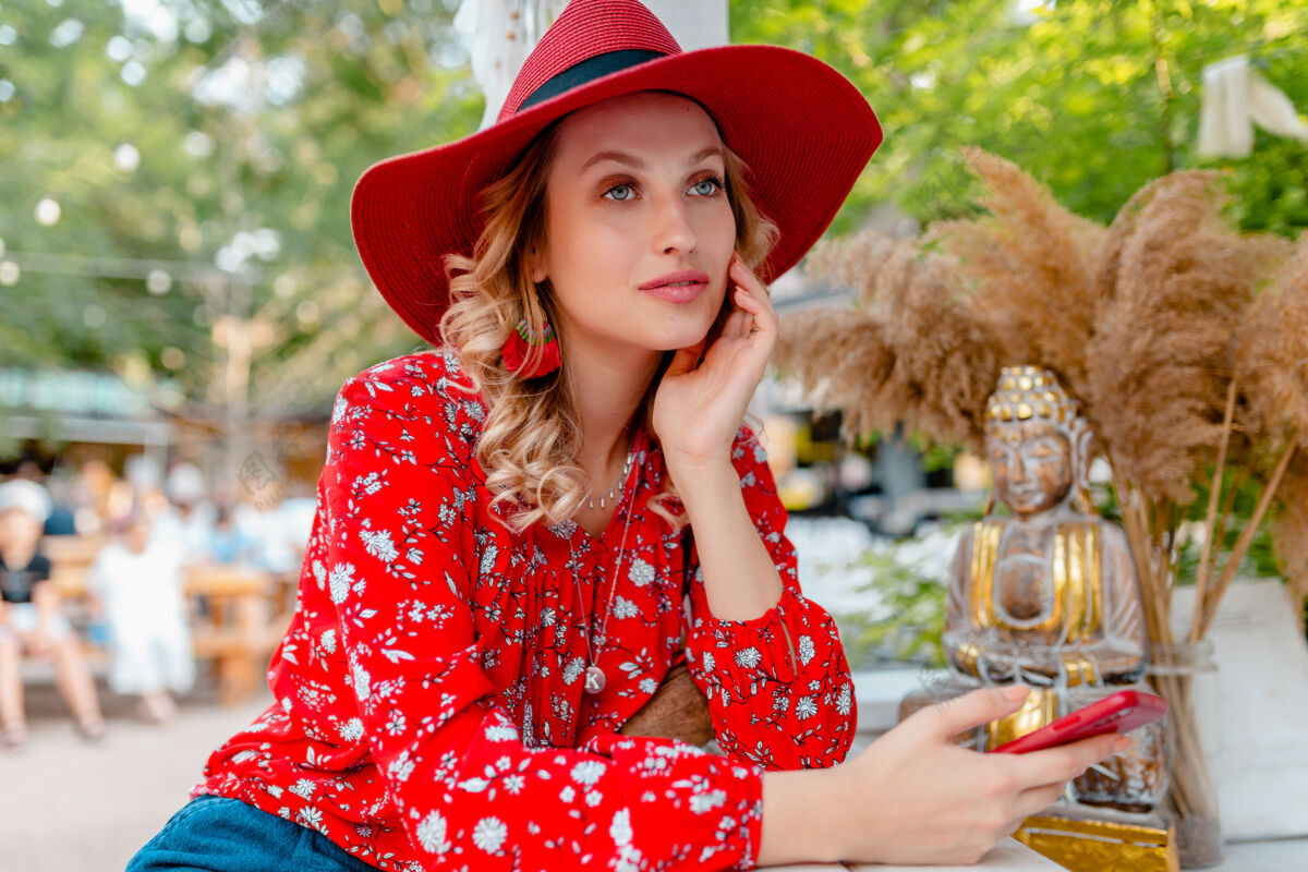 手机迷人的时尚金发微笑的女人在稻草红帽子和衬衫夏季时尚服装举行使用智能手机咖啡厅优雅配件女人