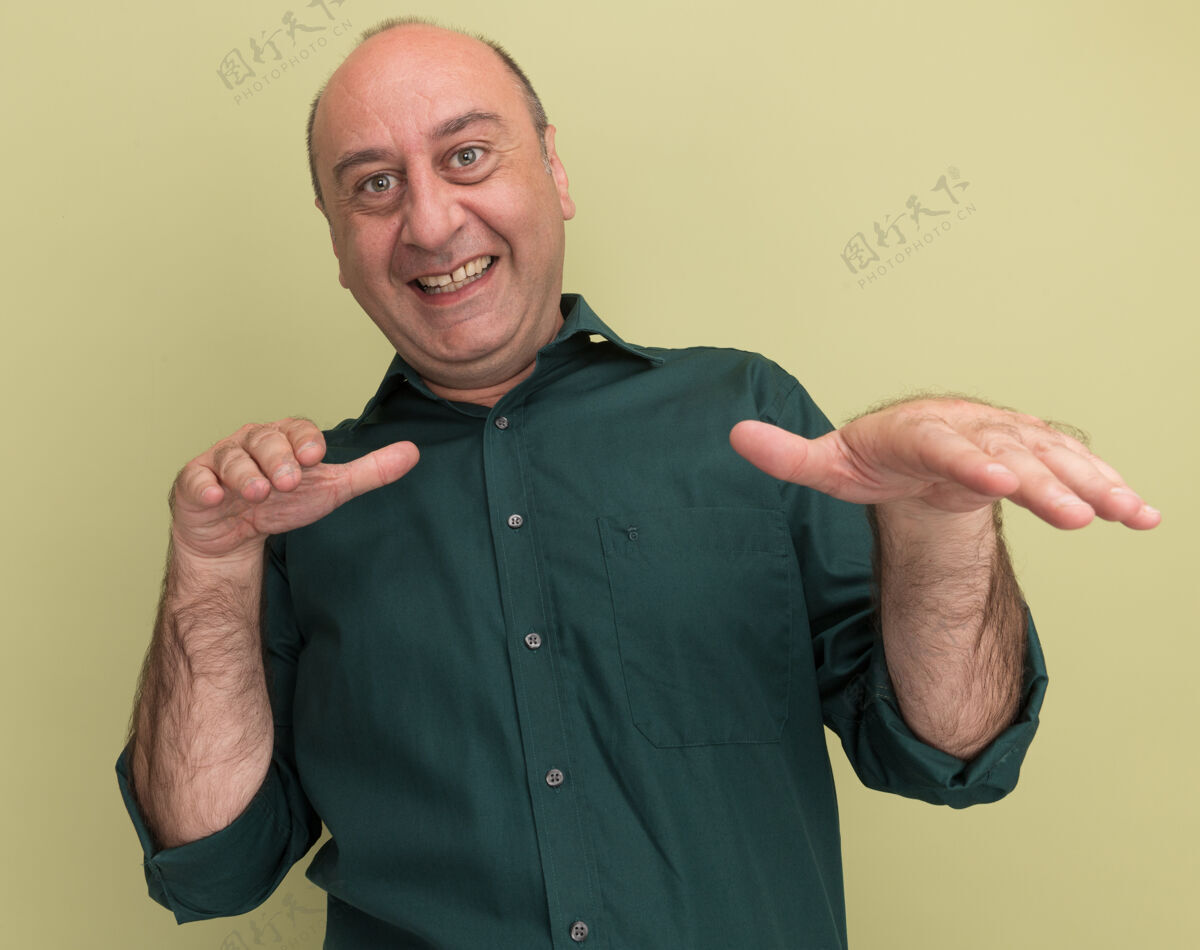 手微笑着的中年男子身穿绿色t恤 在橄榄绿的墙上对着镜头伸出双手橄榄中年穿