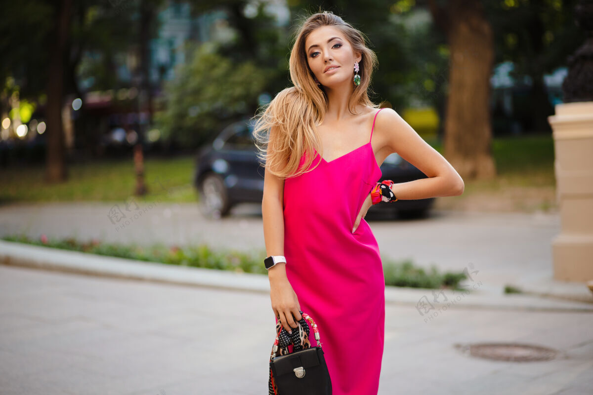 女人优雅迷人的女人穿着粉色性感夏装 手拿手袋走在街上时尚女性浪漫