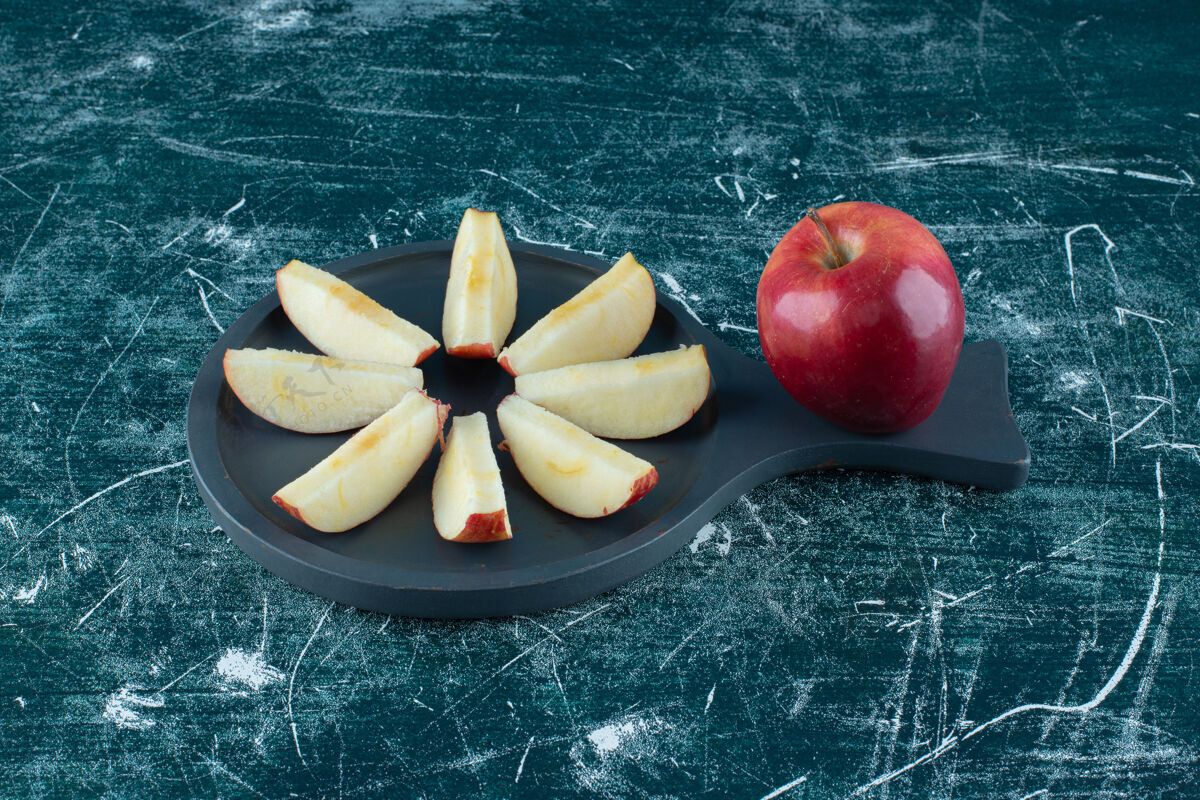 苹果把整个红苹果切成薄片放在深色木板上生有机多汁