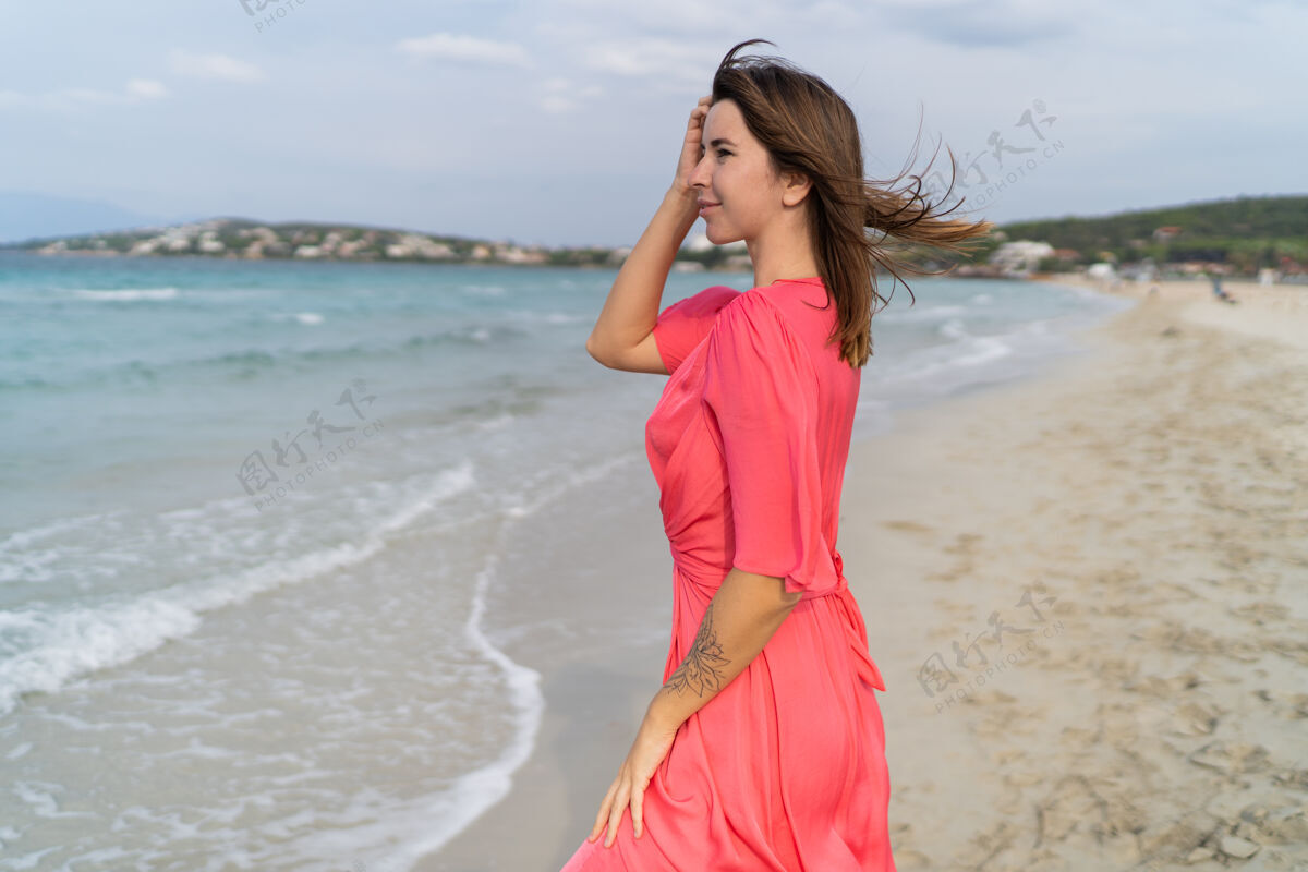 衣服夏日快乐性感的女人穿着华丽的粉色连衣裙在沙滩上摆姿势能量活跃沙滩
