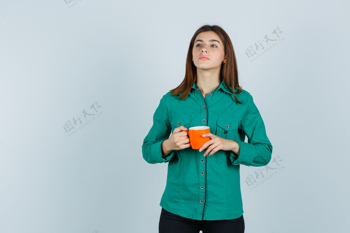 治疗穿着衬衫的年轻女士手里拿着一杯橘色的茶 看上去很自信 正对着前方信心微笑女士
