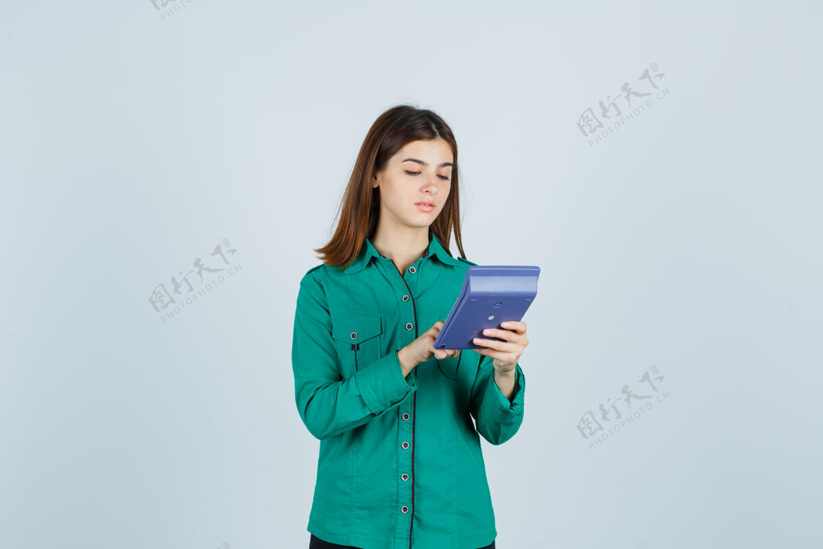 候选人身着绿色衬衫的年轻女士在计算器上计算的肖像 正看着忙碌的前视图专业人士水平职业