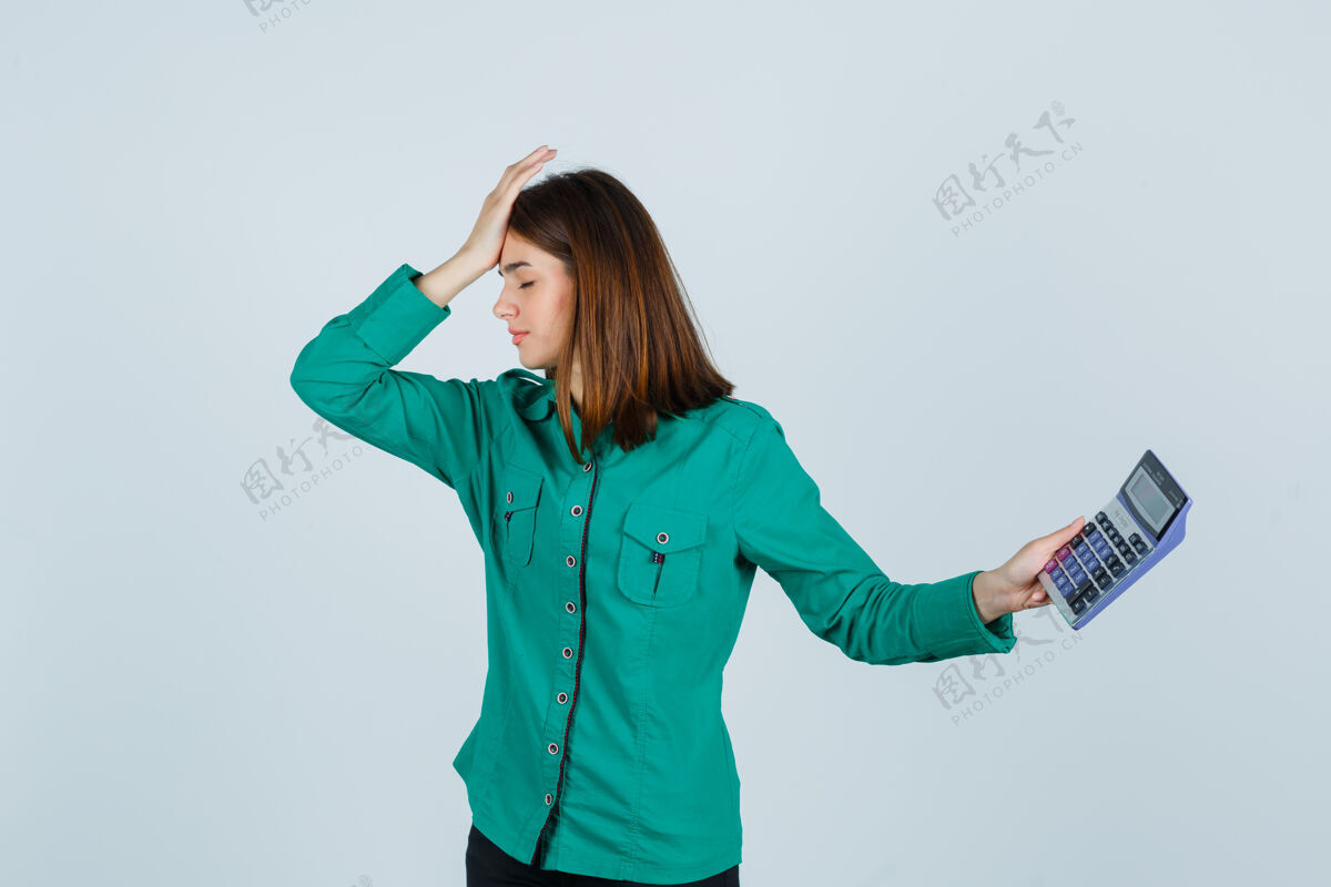 女人年轻女士拿着计算器 手放在额头上 穿着绿色衬衫 看上去很沮丧前视图而女侵略性