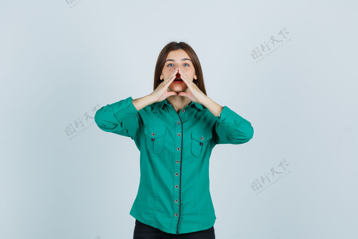 女人照片中的年轻女士手拉手靠近嘴边 穿着绿色衬衫讲着秘密 看着好奇的前景色思想女性秘密