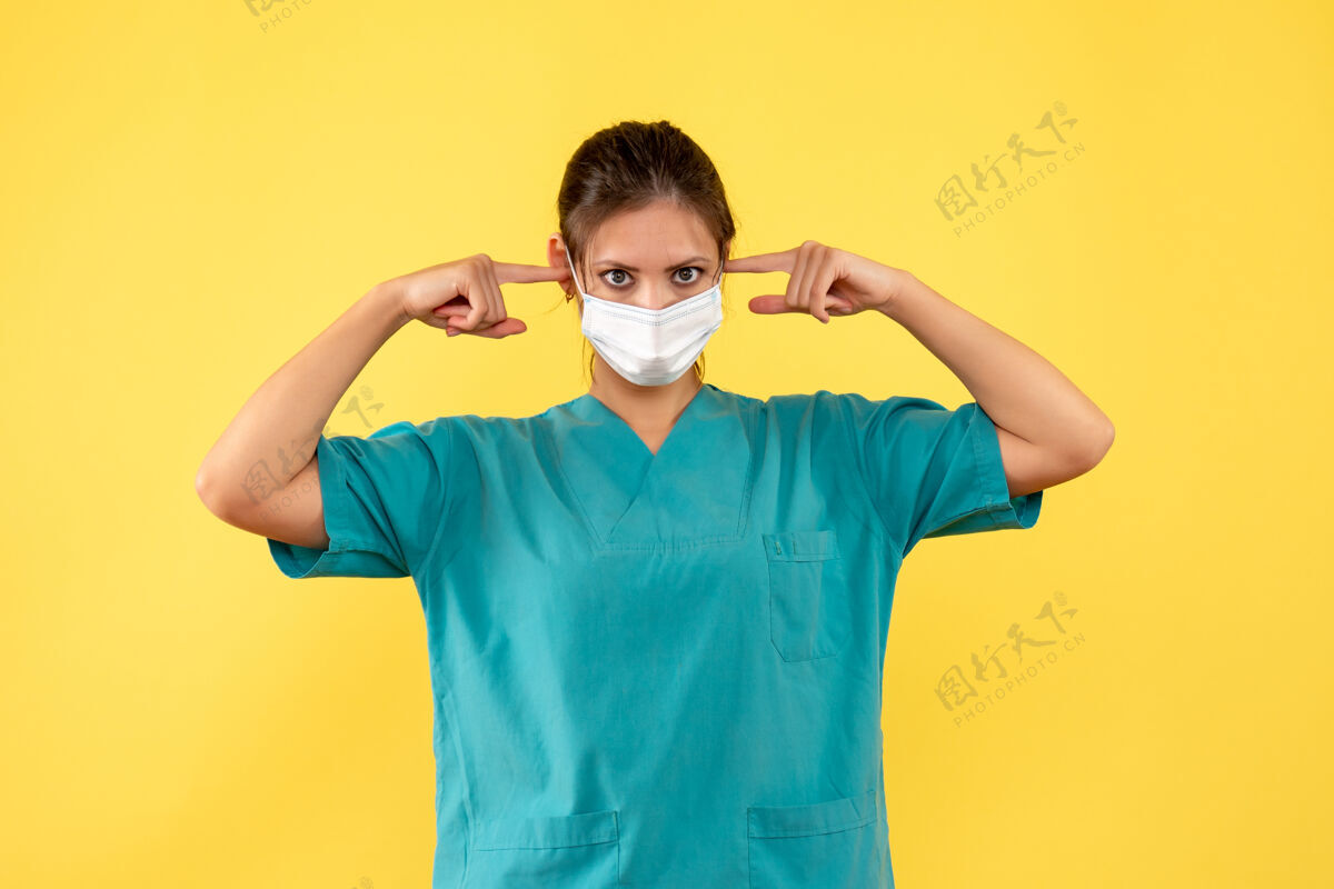 流行病前视图黄色背景上穿着医用衬衫和面罩的女医生女医生正面黄色