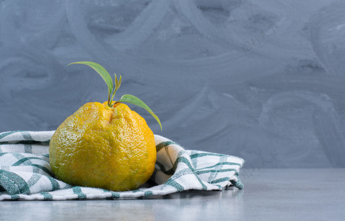 橘子在大理石背景上的毛巾上放一个橘子水果美味柑橘