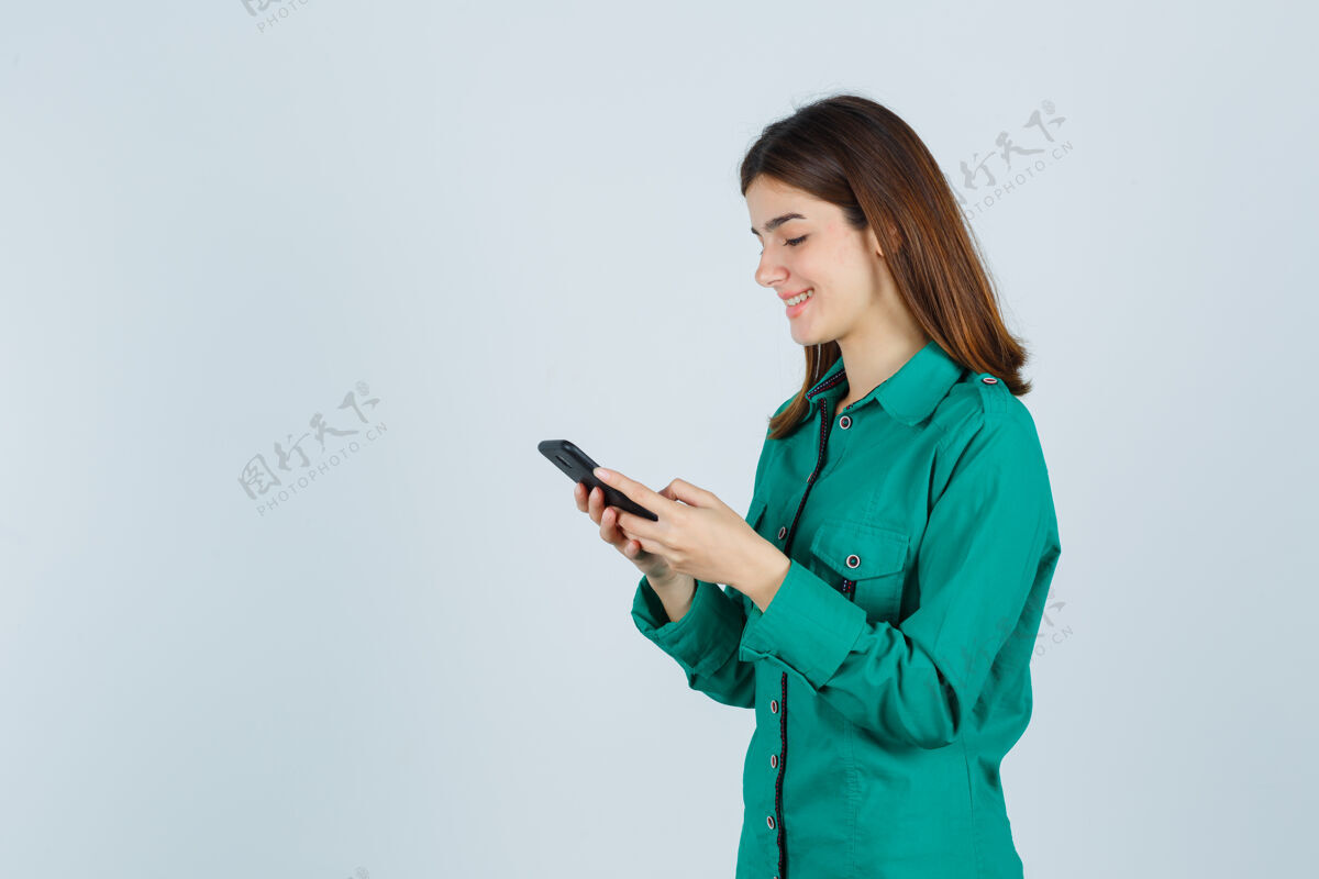 年轻年轻女孩穿着绿色上衣 黑色裤子在电话里写信息 看上去很开朗 正面照休闲女孩人