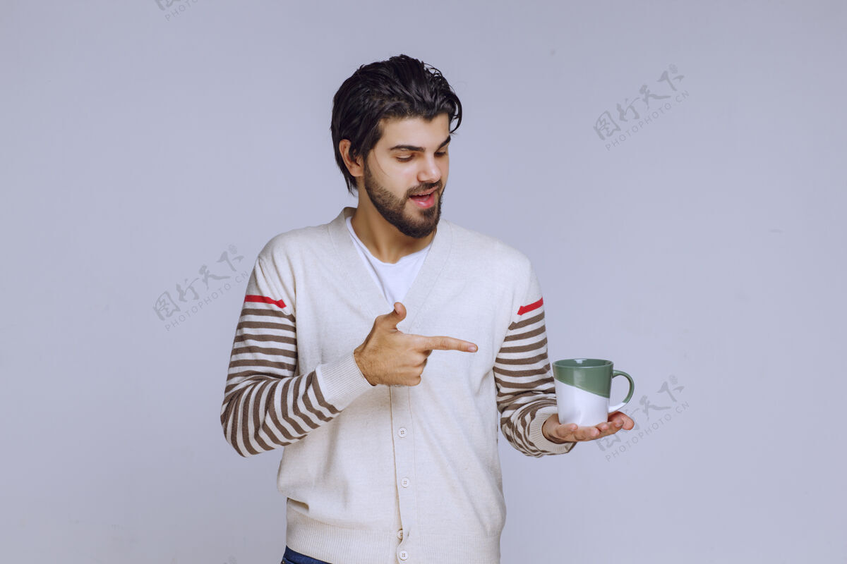 雇员一个穿着白衬衫的男人拿着一个咖啡杯指着它休闲人人类