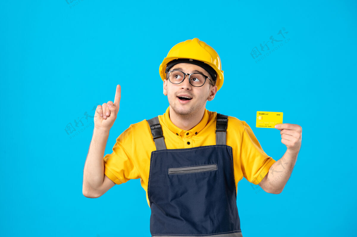 服务身穿黄色制服 信用卡在蓝色上的男工人的正面视图工作建筑商承包商