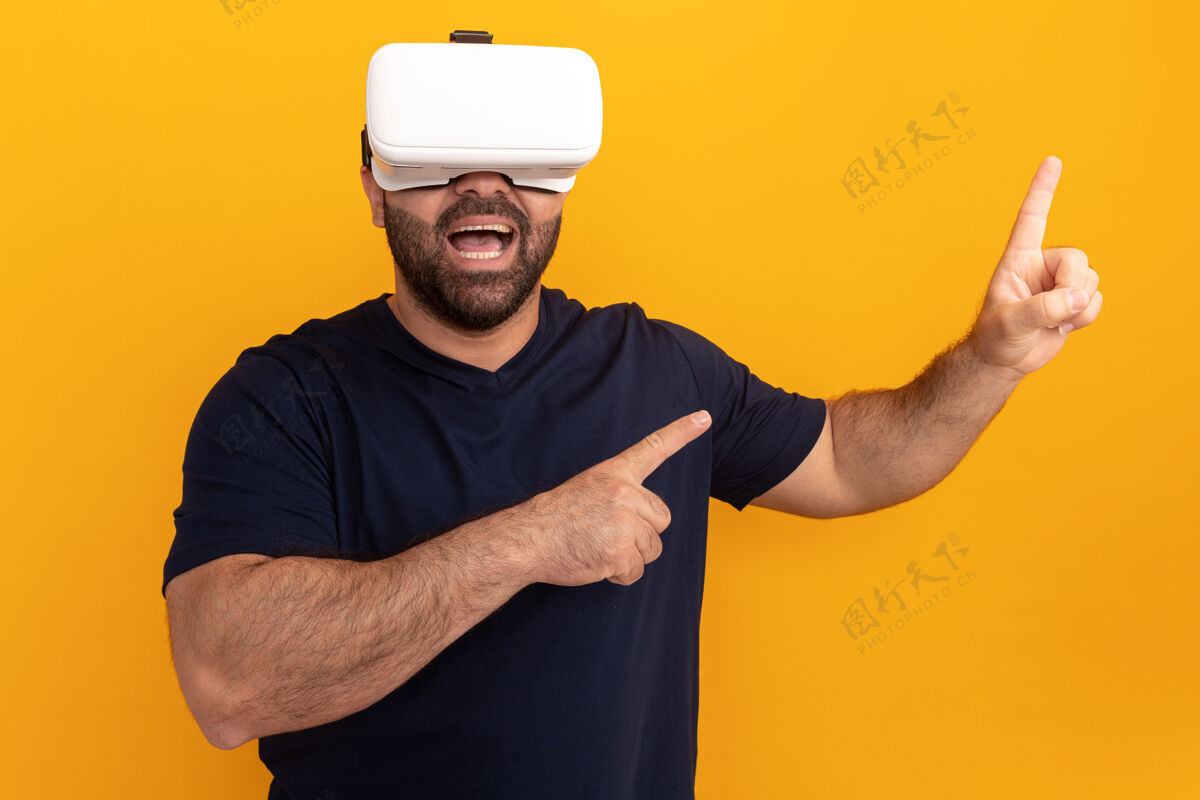 现实一个留着大胡子的男人穿着海军t恤 戴着一副虚拟现实的眼镜 用食指指着站在橙色墙上的一边目录人虚拟