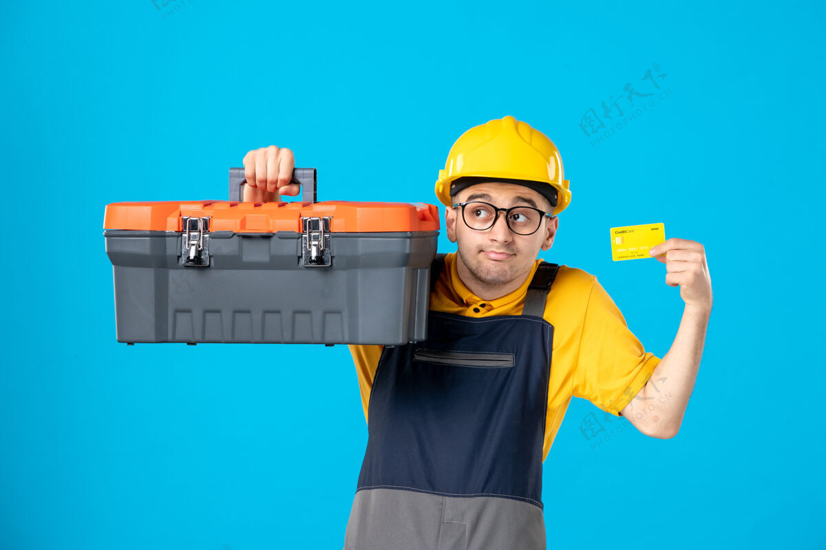 建筑工人穿黄色制服的男工人的正面图 工具箱在蓝色上制服杂工工作
