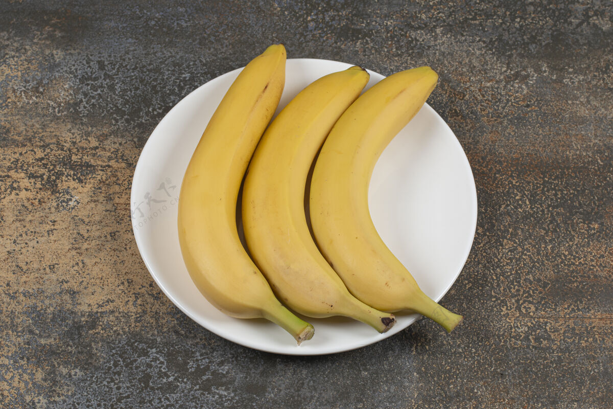 成熟白盘子里放三个熟香蕉水果热带健康