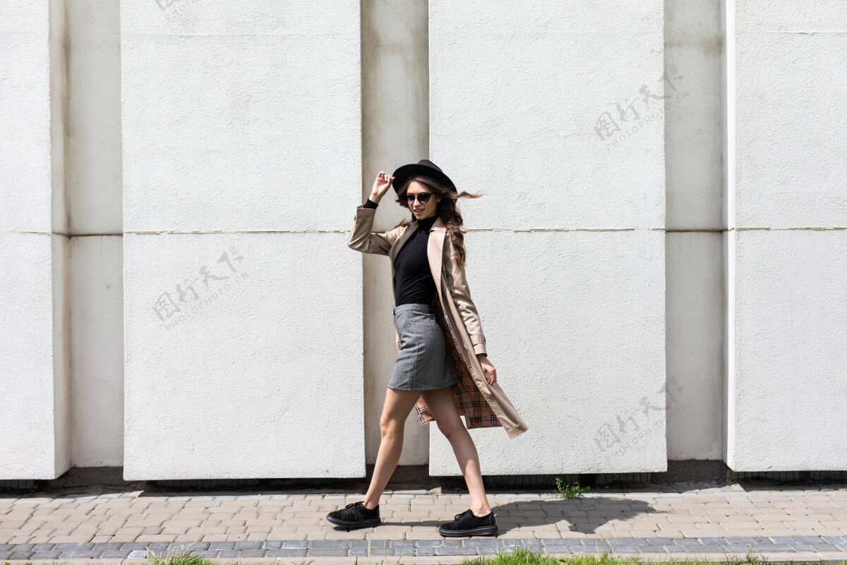 模型一个戴着墨镜和黑帽子的年轻女子在街上行走的画像一起春天时尚
