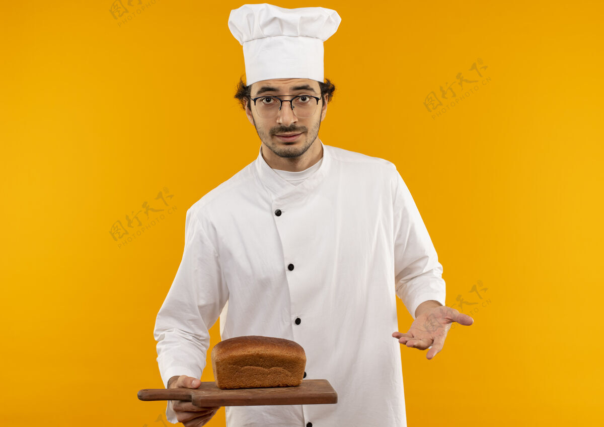 厨师年轻的男厨师穿着厨师制服 戴着眼镜 拿着面包放在砧板上年轻持有男性