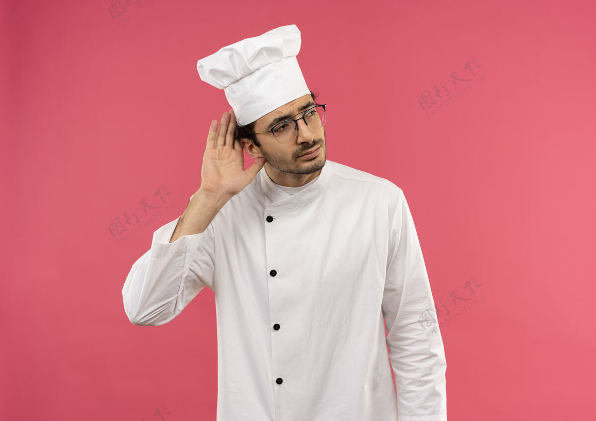 粉红看着身边想着的年轻男厨师穿着厨师制服 戴着眼镜 显示出倾听的姿态男性厨师男