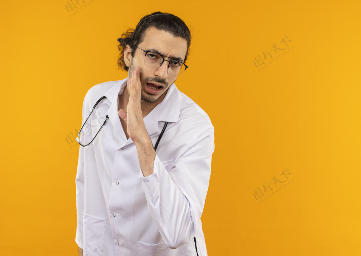 年轻戴着医用眼镜 穿着医用长袍 带着听诊器的年轻医生低声说医疗耳语医生