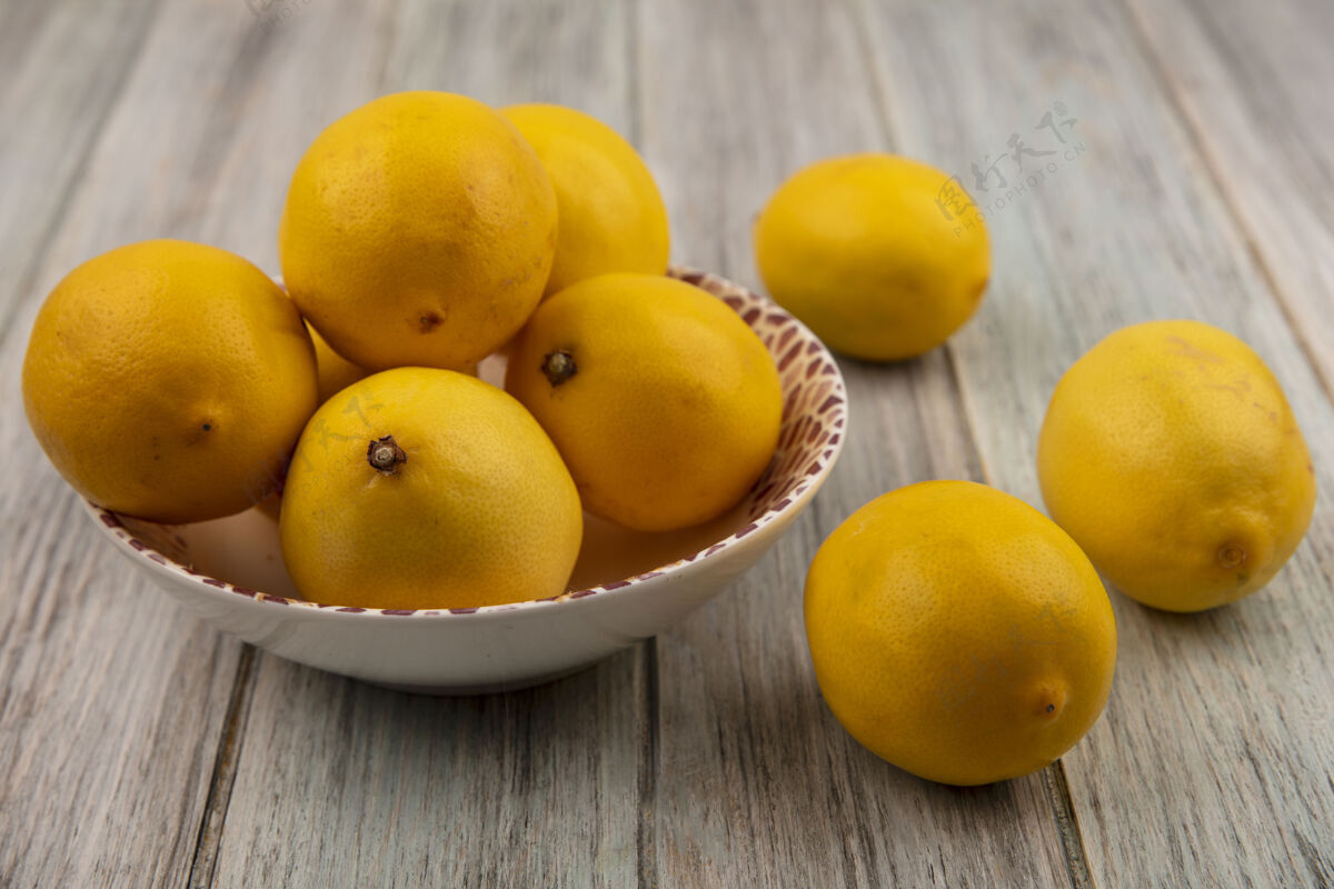美味俯视图富含维生素的整个柠檬在一个碗与柠檬隔离在一个灰色的木制表面美味切片柑橘