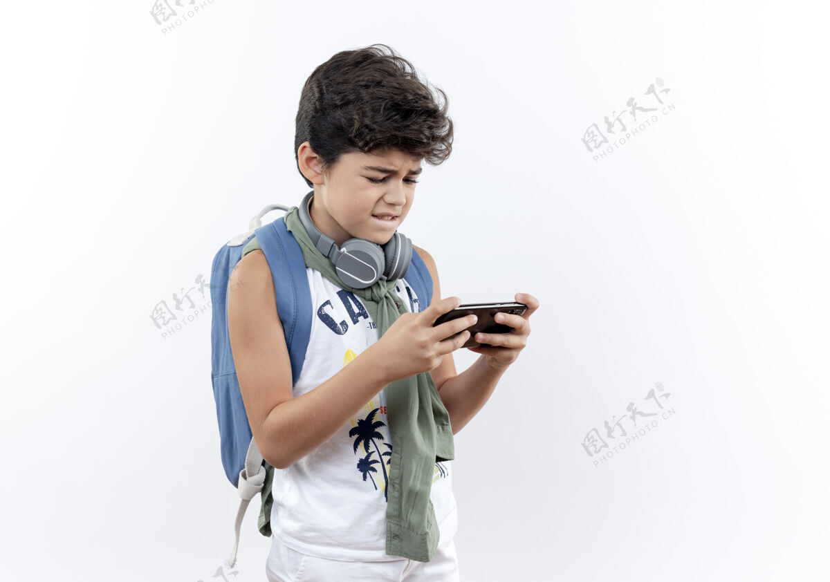 孩子带着背包和耳机玩电话的小男孩小学生学生男孩
