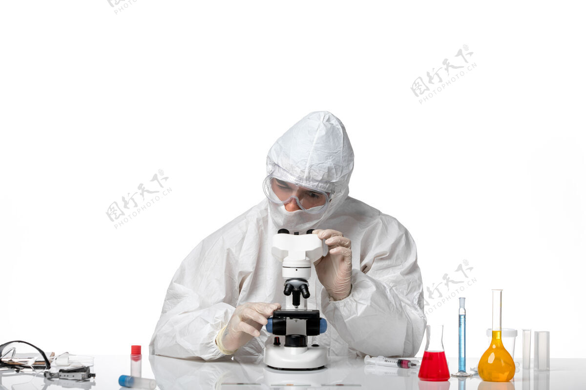 外套前视图男医生穿着防护服 戴着面罩 在空白处使用显微镜专业口罩医生