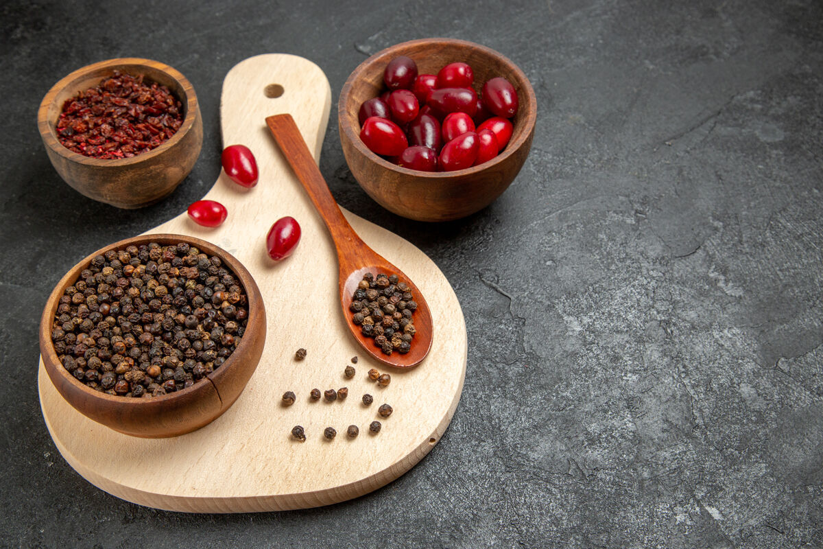 农产品在深灰色的桌子上可以看到新鲜的红色山茱萸和调味品石榴美味的黑樱桃