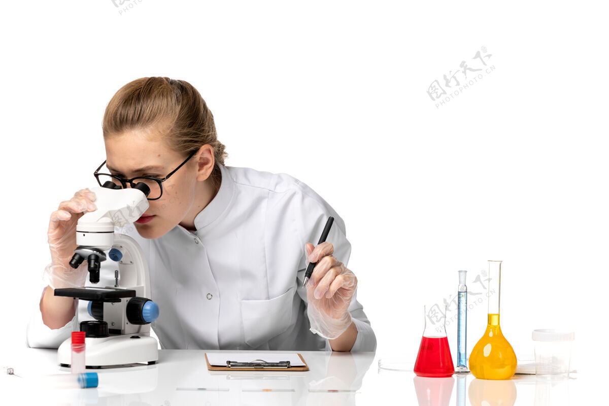 办公室前视图穿着白色医疗服的女医生在白色空间使用显微镜疾病病毒套装