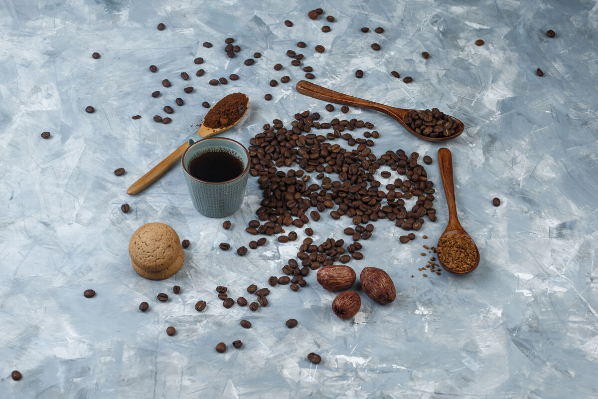 木头一套速溶咖啡 咖啡粉 咖啡豆在木制勺子 饼干和咖啡豆 咖啡杯浅蓝色大理石背景高角度视图时钟饼干大理石